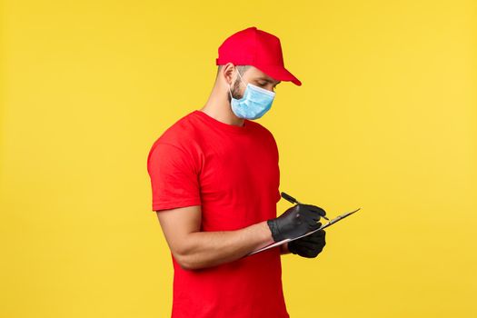 Express delivery during pandemic, covid-19, safe shipping, online shopping concept. Busy courier in red uniform and medical mask, gloves, writing down information about order or tracking.