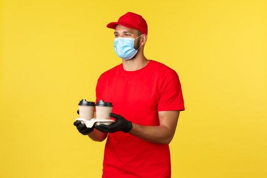 Takeaway delivery, food and drinks, covid-19 quarantine and preventing virus concept. Nice smiling courier bring order, drive through employee handing coffee to customer, wear medical mask.