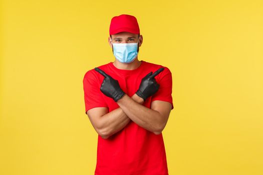 Express delivery during pandemic, covid-19, safe shipping, online shopping concept. Courier in red uniform cap and t-shirt, medical mask gloves, pointing sideways, show left and right variants.