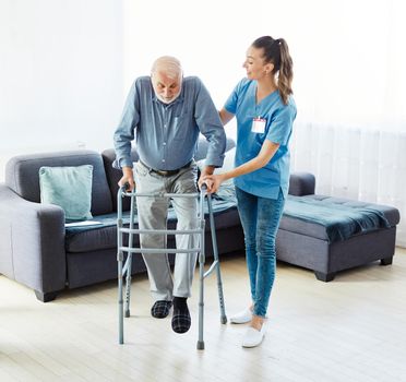 Doctor or nurse caregiver with senior man using walker assistanece at home or nursing home