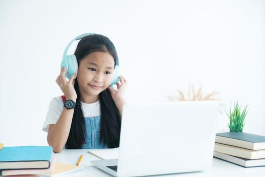 Primary school girl studying homework during online lesson at home, social distance during quarantine, self-isolation, online education concept, home school, study online video call teacher.