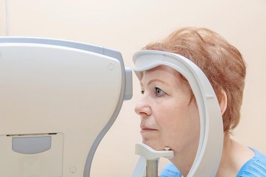 An adult woman at an ophthalmologist's appointment checks her vision on a special apparatus. Close-up