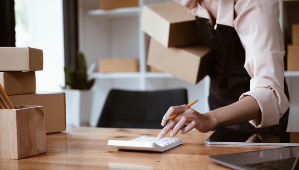 Starting a Small Business, SME Owners, Female Entrepreneurs Check online orders via calculator To prepare to pack boxes for sale to SME customers online business ideas.