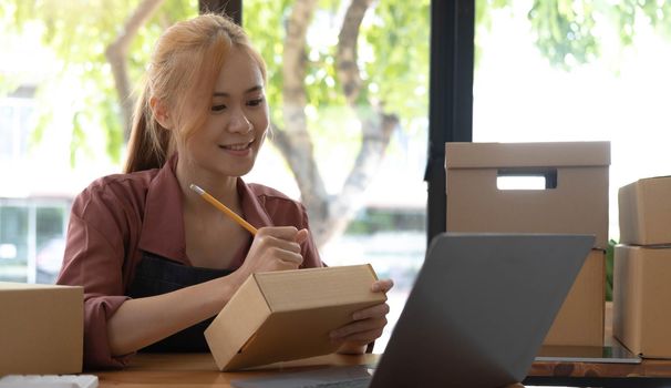 Portrait of Asian young woman SME working with a box at home the workplace.start-up small business owner, small business entrepreneur SME or freelance business online and delivery concept..