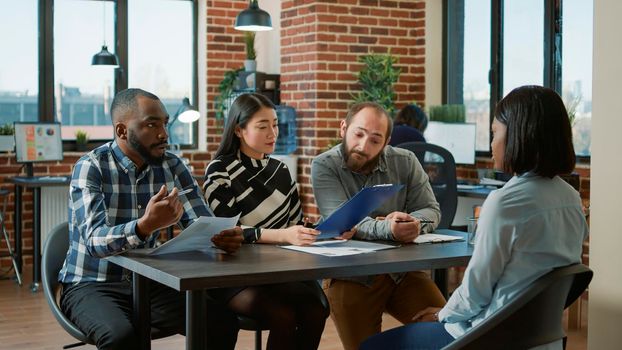 Diverse group of workers attending job interview meeting with applicant, talking about work experience and cv information. Female candidate cooperating with HR department employees.