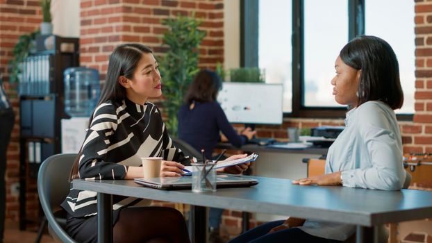 Multiethnic team of women meeting to discuss company vacancy, making job offer. HR worker interviewing female applicant about work experience and recruitment information. Hiring concept.