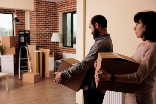 Happy man and woman moving together in new family house to start lifestyle beginnings. Buying first apartment flat and celebrating life event, decorating property space with furniture.