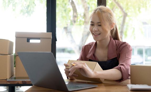 Portrait of Asian young woman SME working with a box at home the workplace.start-up small business owner, small business entrepreneur SME or freelance business online and delivery concept..