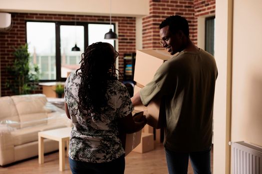 African american people carrying furniture to move in new apartment property, using boxes to decorate rented household. Moving in house together to start new beginnings on loan.