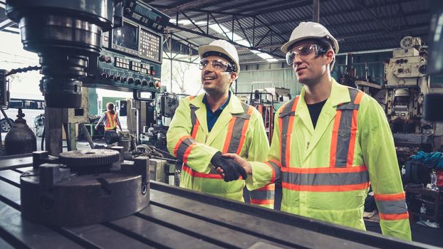 Factory workers handshake with team member in the factory . Industry people teamwork and trust concept .