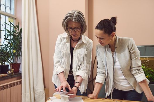 Diligent team of fashion designers working in a fashion design studio discussing patterns for sewing clothes in a tailoring workshop. Seamstress, tailor, sewer, dressmaker, creative occupation concept