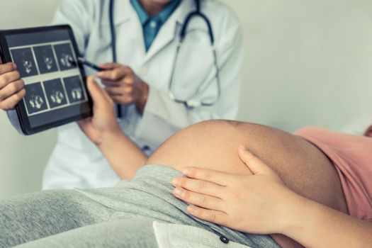 Happy pregnant woman visit gynecologist doctor at hospital or medical clinic for pregnancy consultant. Doctor examine pregnant belly for baby and mother healthcare check up. Gynecology concept.