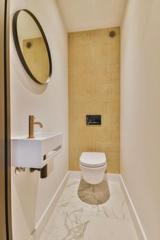 Wall hung toilet and small sink in corner in lavatory room with beige tile