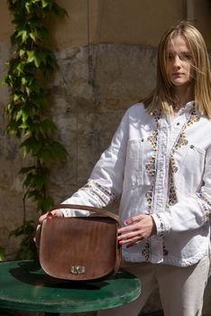 woman holds small brown women's leather bag . selective focus. Street photo