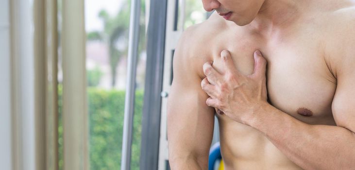 Muscular man touching his chest in fitness center. Bodybuilding concept.