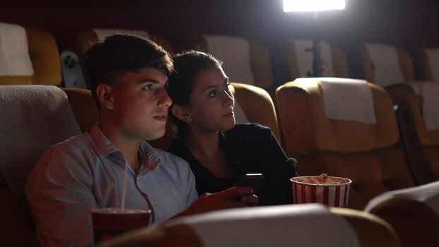 Men playing games on mobile phones he makes his girlfriend annoy and Interfere with watching the movie.