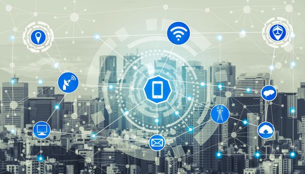 Smart city wireless communication network with graphic showing concept of internet of things ( IOT ) and information communication technology ( ICT ) against modern city buildings in the background.