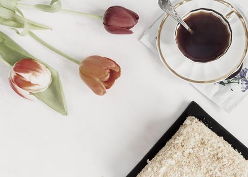 Alternative coffee substitute: a hot decaffeinated drink made from natural chicory, on the table in a white cup. Next to a delicious cake and flowers. Top view with copy space. Flat lay