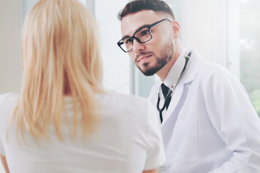 Male doctor is talking with female patient in hospital office. Healthcare and medical service.