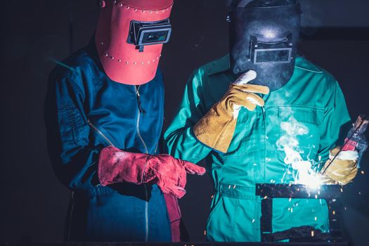 Metal welding steel works using electric arc welding machine to weld steel at factory. Metalwork manufacturing and construction maintenance service by manual skill labor concept.