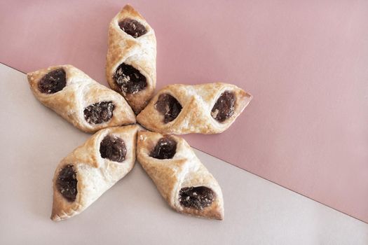 On a two-color background, delicious puff pastry cookies stuffed with raspberry jam. Top view with copy space. Flat lay