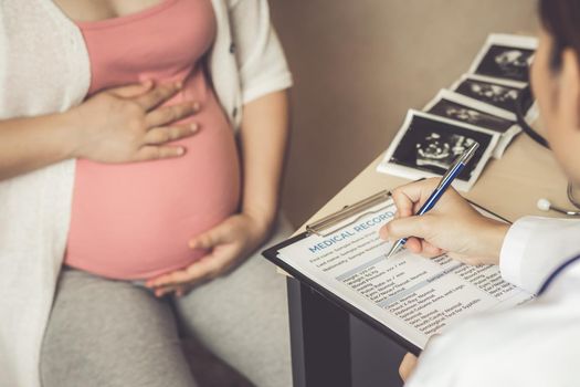 Happy pregnant woman visit gynecologist doctor at hospital or medical clinic for pregnancy consultant. Doctor examine pregnant belly for baby and mother healthcare check up. Gynecology concept.