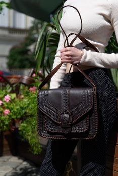 small brown women's leather bag with a carved pattern. street photo