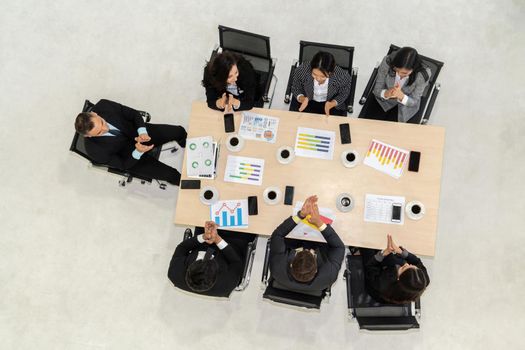 Successful business people celebrate together with joy at office table shot from top view . Young businessman and businesswoman workers express cheerful victory showing success by teamwork .