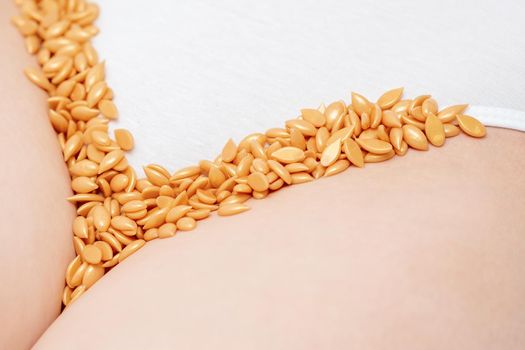 Close up of wax beans or seeds lying in row on bikini zone of young woman