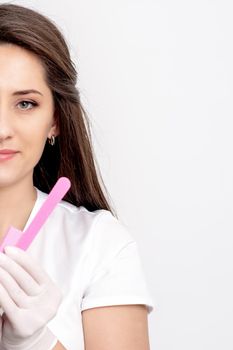 Portrait of beautiful young caucasian woman manicure master holding manicure tools on white background