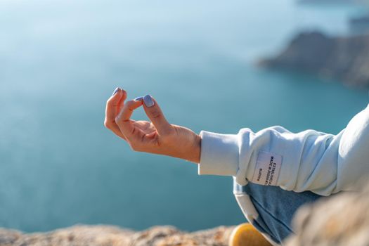 yoga, gesture and healthy lifestyle concept - hand of meditating yogi woman showing gyan mudra over sea sunset background.