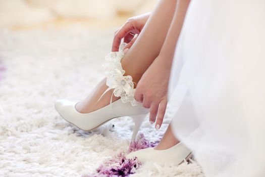 Bride's morning. The bride is putting her shoes on.