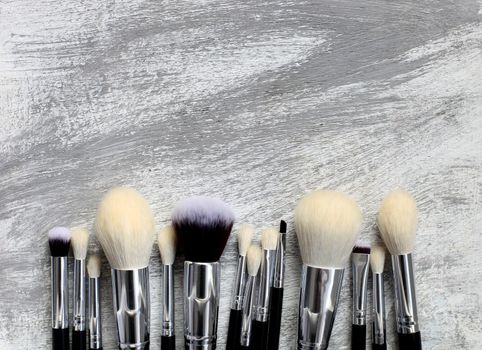 Various makeup brushes on gray stone