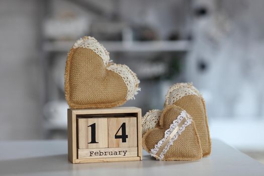 Valentines day concept. Hand make yarn heart beside wooden block calendar set on Valentines date 14 February on table and bright room background