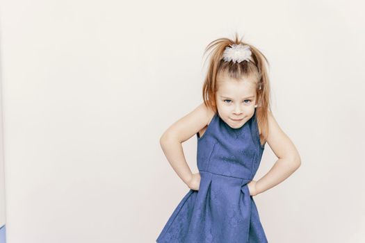 cute 5-6 year old girl in a blue dress posing in the studio. emotion of anger