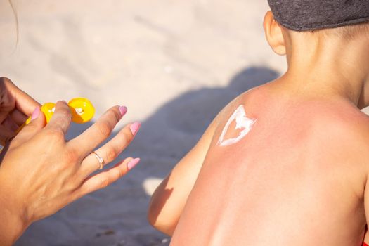 Mom puts sunscreen on Sin's back in the shape of a heart. selective focus