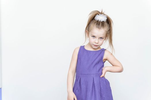 cute 5-6 year old girl in a blue dress posing in the studio