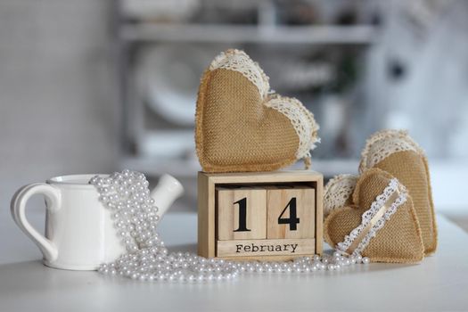 Valentines day concept. Hand make yarn heart beside wooden block calendar set on Valentines date 14 February on table and bright room background