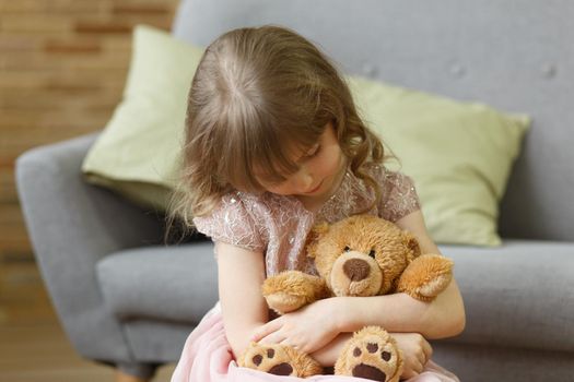 Adorable little girl with teddy bear looking at camera at home, smiling preschool pretty child with beautiful happy face posing alone on sofa, cute positive cheerful kid headshot portrait