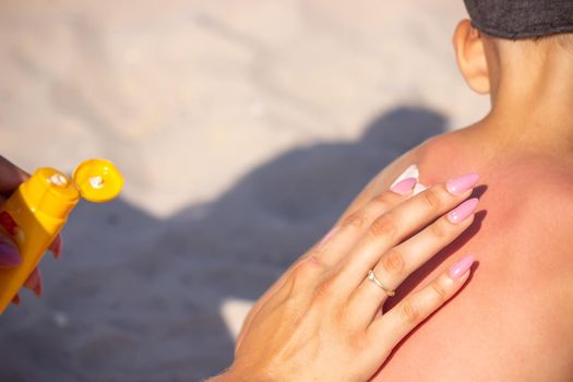 Mom puts sunscreen on Sin's back in the shape of a heart. selective focus