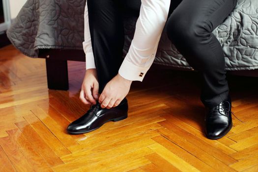 Preparing for wedding. Groom buttoning cufflinks on white shirt before wedding. True men's accessory. Groom's clothes.