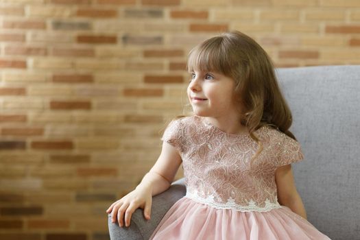 Adorable little girl looking at camera at home, smiling preschool pretty child with beautiful happy face posing alone on sofa, cute positive cheerful kid headshot portrait