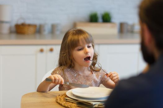 Small girl sets the table for a meal at a family dinner.