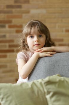 Adorable little girl looking at camera at home, smiling preschool pretty child with beautiful happy face posing alone on sofa, cute positive cheerful kid headshot portrait