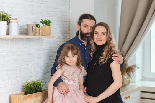 Family on the light kitchen. Pregnant woman with her husband and little daughter.