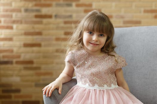 Adorable little girl looking at camera at home, smiling preschool pretty child with beautiful happy face posing alone on sofa, cute positive cheerful kid headshot portrait
