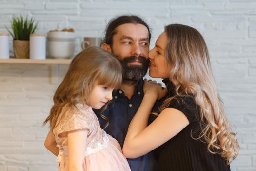 Family on the light kitchen. Pregnant woman with her husband and little daughter.