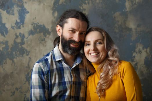 Love and relationship concept. Happy adult couple hugging, smiling wide and looking at camera, standing together on blue abstract background