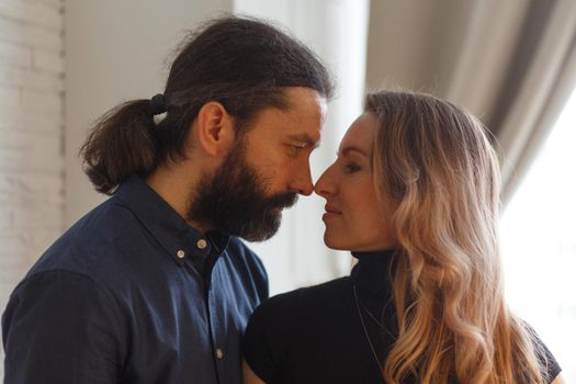 Man embracing pregnant partner in kitchen. Adult family pregnancy concept. Future parents in home outfit embrace standing in the kitchen, looking at each other, kissing. Healthy Lifestyle.