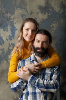 Love and relationship concept. Happy adult couple hugging, smiling wide and looking at camera, standing together on blue abstract background